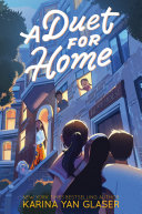 The backs of three people looking up at a building with an adult coming out the door and children leaning out the windows.