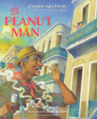 It is a sunny day, a man is standing carrying a box filled with warm cones of peanuts and yelling for customers. Behind him there are yellow apartment buildings with blue balconies.