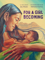 A woman looking lovingly down at the baby she is holding with mountains in the background.