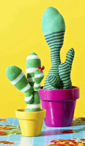 Fake cactuses made from green socks displayed in flower pots