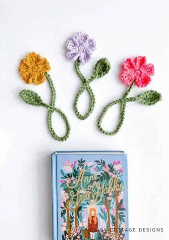 Three crochet floral bookmarks laid out above a book.