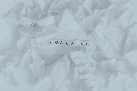 White crumpled paper with the word hoarding in the center spelled with scrabble tiles