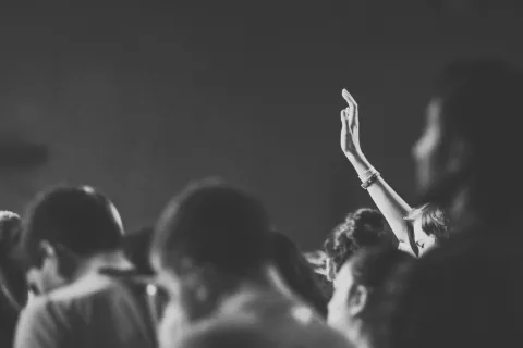 black and white image of a person raising their hand in a small crowd