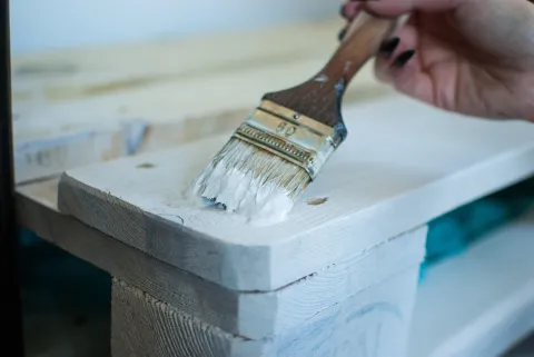 photograph of a paintbrush painting a piece of furniture