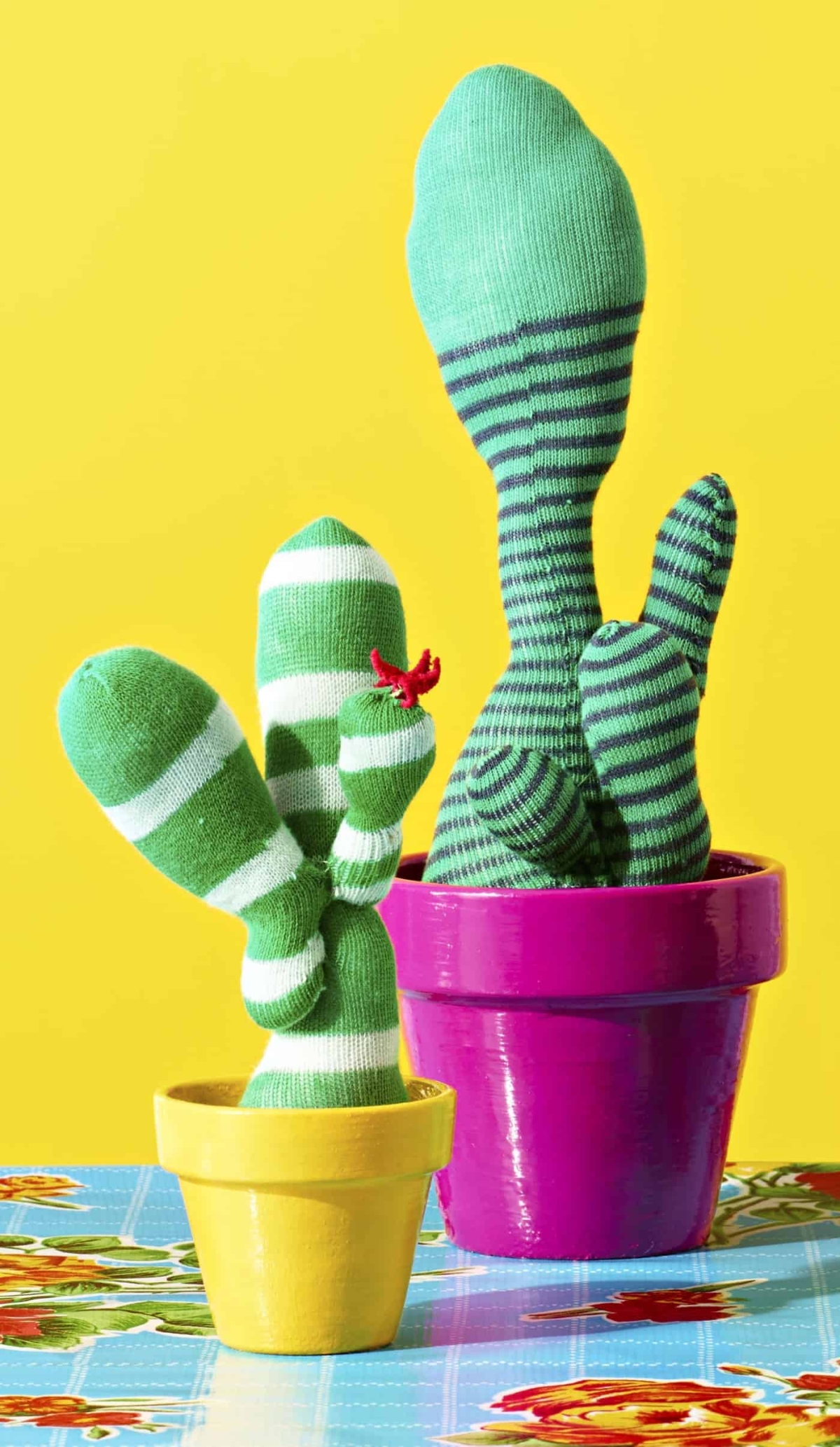Fake cactuses made from green socks displayed in flower pots
