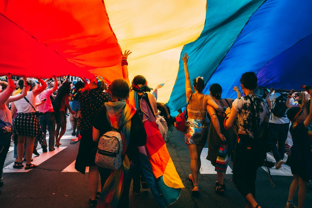 People underneath a large rainbow banner