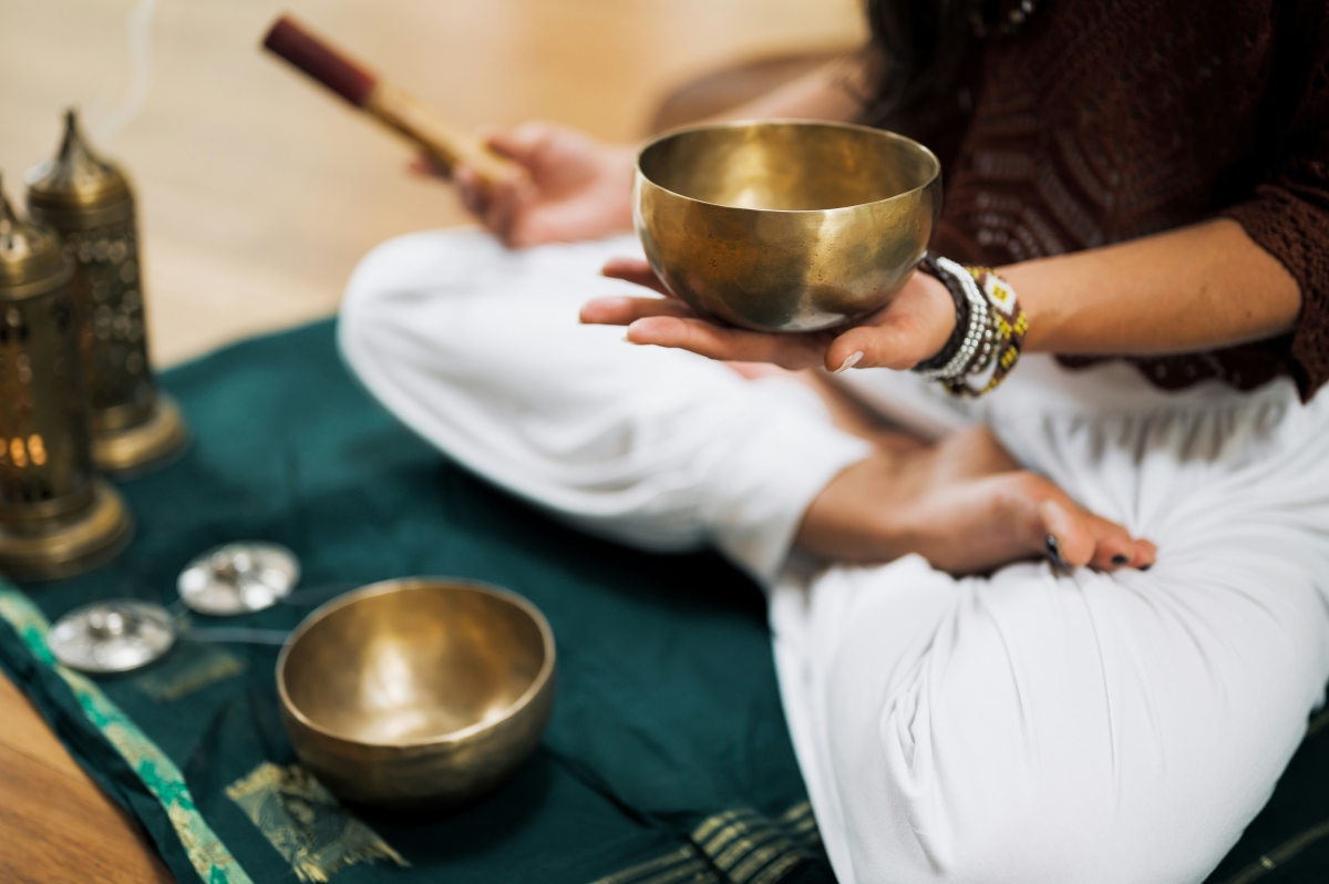 A photograph of a seated person holding a sound bowl